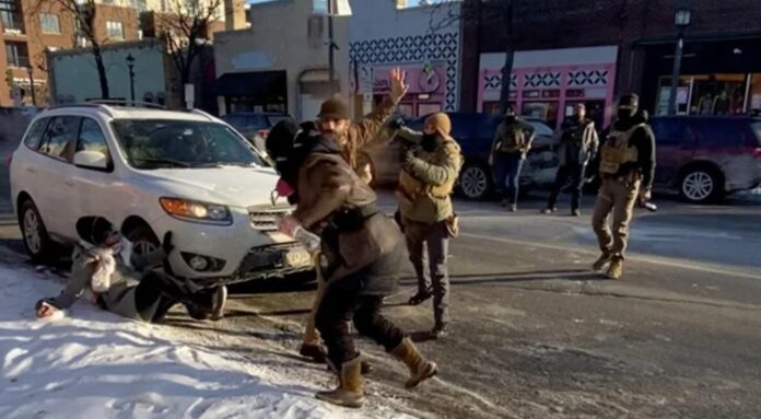 Alex Pretti, one hand on his phone, one hand in the air.